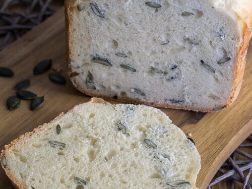 Kürbisbrot aus dem Brotbackautomat mit Joghurt, oben belegt mit Kürbiskernen, eine Scheibe abgeschnitten.