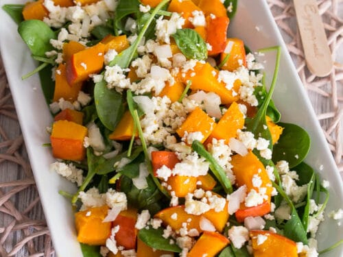 Kürbissalat mit Spinat, geröstetem Butternuss-Kürbis und zerbröseltem Feta auf ovalem weißen Teller.