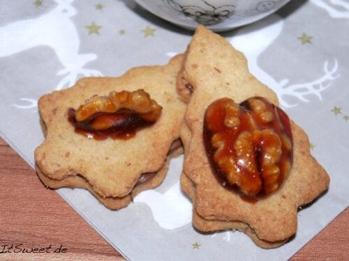 Zwei Walnussplätzchen, belegt mit karamellisierten Walnüssen.