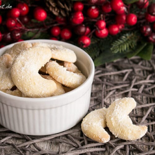 Vanillekipferl Plätzchen 3 Weiße Schale, gefüllt mit halbmondförmigen Vanillekipferln, bestäubt mit Puderzucker.