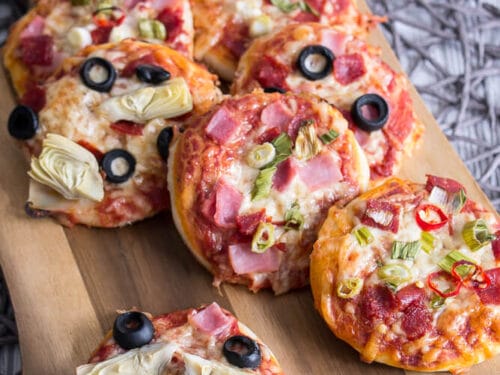 Mini-Pizzen, belegt mit Schinken, Oliven, Artischocken und Paprika.