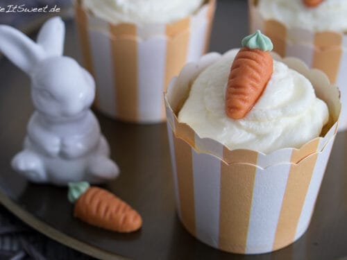 Karottenmuffins mit Mandeln, weißem Frosting und Karottendekor.