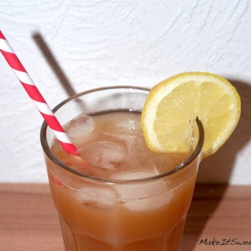 Pfirsich Eistee selber machen ohne Zucker 3 Ein Glas Pfirsich-Eistee mit einer Zitronenscheibe und einem rot-weißen Strohhalm auf einer Holzfläche.