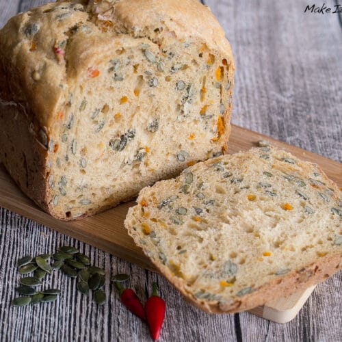 Kürbisbrot mit Chili: Kürbisbrot mit Kernen, geschnitten, mit Kürbiskernen und roten Chilischoten.