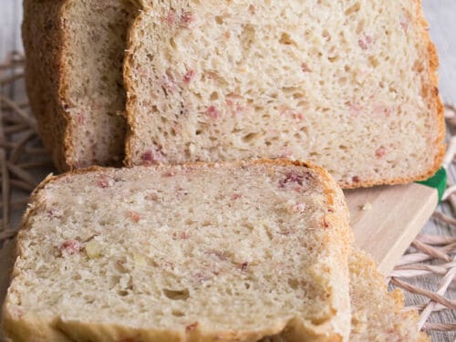 In Scheiben geschnittenes hausgemachtes Kartoffelbrot mit Speck auf einem Holzbrett.