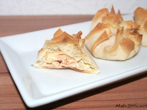 Lachstaschen mit cremiger Füllung, eine aufgeschnitten auf einem weißen Teller, dahinter weiteres Gebäck.