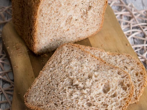 Joghurtbrot mit Kleie mit zwei Scheiben auf einem Schneidebrett, das die Textur des Brotes zeigt.