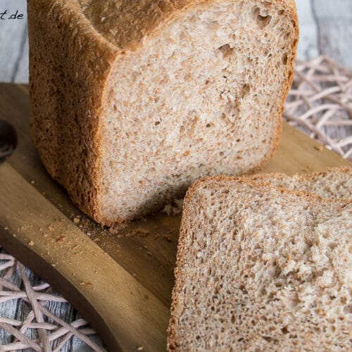 Joghurtbrot mit Kleie und einer dicken Scheibe auf einem hölzernen Schneidebrett.