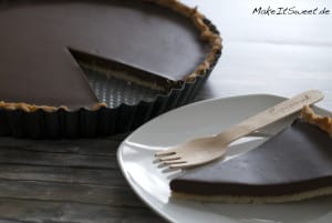 Schokoladentorte mit herausgeschnittener Scheibe und reichhaltiger Schokoladenfüllung auf einem weißen Teller mit einer Holzgabel.