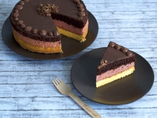 Dreischichtiger Deutschland-Torte-Schokoladenmousse-Kuchen mit einem Stück auf einem Teller und einer Holzgabel.