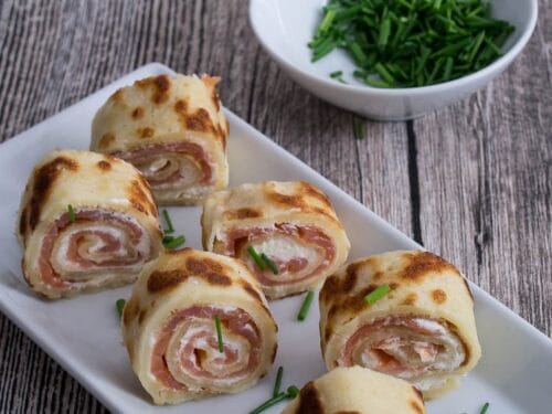 Sechs kleine Räucherlachs Pfannkuchen mit Frischkäse als Fingerfood angerichtet.