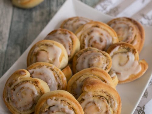 Mehrere Mini Hefeschnecken mit Nuss auf einem länglichen Teller.