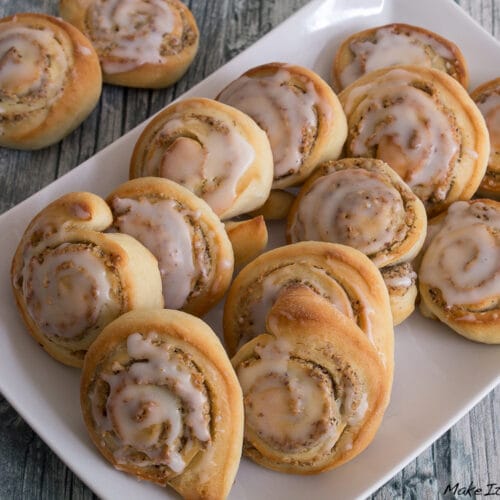 Mini Hefeschnecken mit Nuss 3 Mini Nuss-Hefeschnecken mit Zuckerguss auf einem weißen rechteckigen Teller.