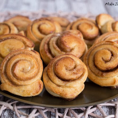 Mini Zimtschnecken 3 Frisch gebackene Mini-Zimtschnecken mit Zimt, Zucker und Gebäck werden auf einem Teller angerichtet.