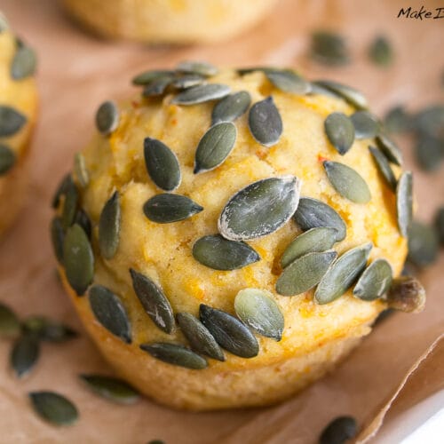 Süße Kürbis Muffins mit Zimt 3 Nahaufnahme von Kürbis-Muffins mit Kürbiskernen obenauf, ausgestellt auf Backpapier.