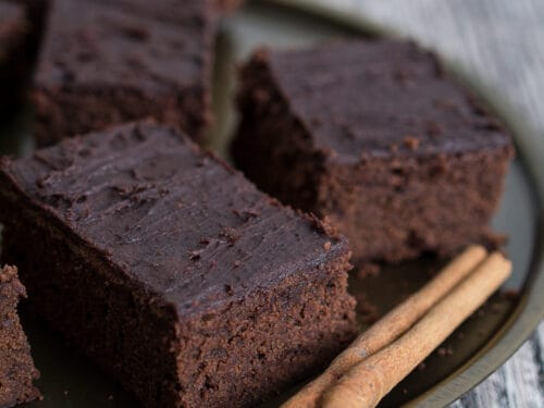 Schokoladen-Brownies mit Zimt und zwei Zimtstangen auf einem Teller.