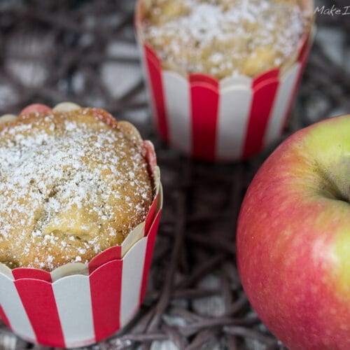 Muffins mit Apfel und Zimt 3 Drei Apfel-Zimt-Muffins in gestreiften Verpackungen, mit Puderzucker bestäubt.