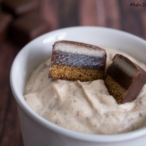 Schale mit cremigem Dessert, gekrönt von zwei mit Schokolade überzogenen Dominostein-Marzipan-Stücken.