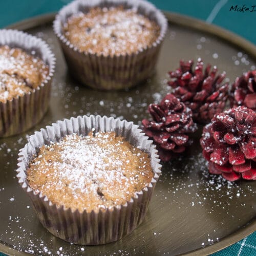 Drei mit Puderzucker bestreute Rotwein-Nuss-Cupcakes auf einem Tablett.