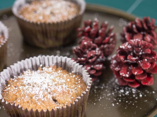 Drei mit Puderzucker bestäubte Rotwein-Nuss-Muffins auf einem Tablett.