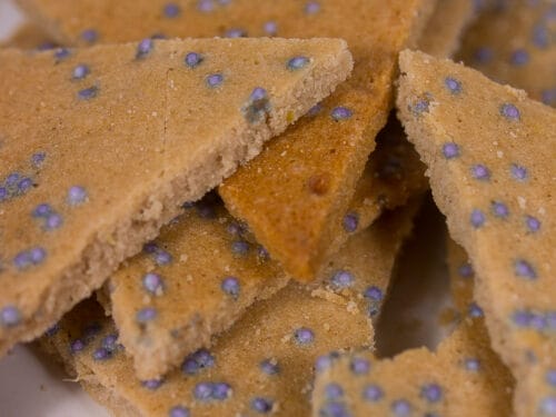 Dreieckige Schoko-Ingwer-Plätzchen mit Streuseln auf einem Teller gestapelt.