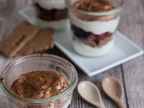 Drei Gläser geschichtetes Tiramisu mit Beeren, einer Creme und Spekulatius-Keksen.