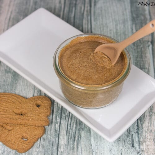 Einfache Spekulatius Creme selber machen 3 Ein Glas Spekulatius-Creme mit einem Löffel auf einem weißen rechteckigen Teller.