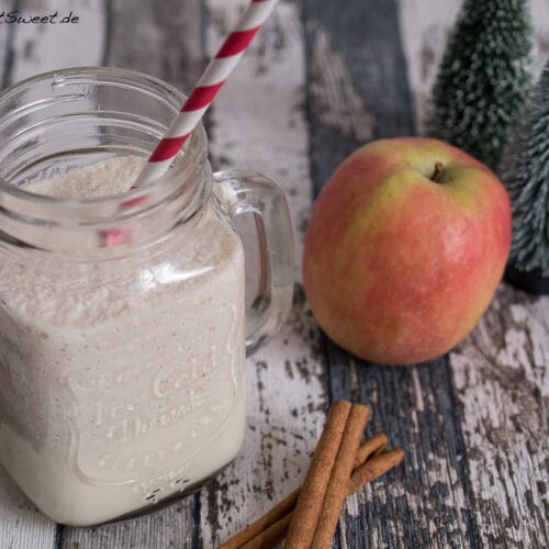 Smoothie mit Apfel und Zimt 3 Smoothie mit Apfel und Zimt in einem Einmachglas mit einem rot gestreiften Strohhalm, Apfel und Zimtstangen daneben.