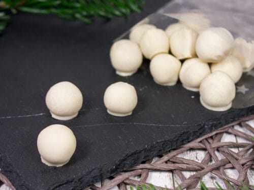 Marzipankugeln aus weißer Schokolade, arrangiert auf einer Schiefertafel.