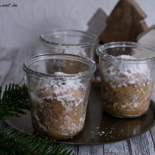 Drei Gläser Stollen im Glas, bestreut mit Puderzucker, mit sichtbaren Stückchen.