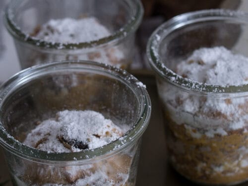 Drei Gläser mit Stollen im Glas, bestreut mit Puderzucker.