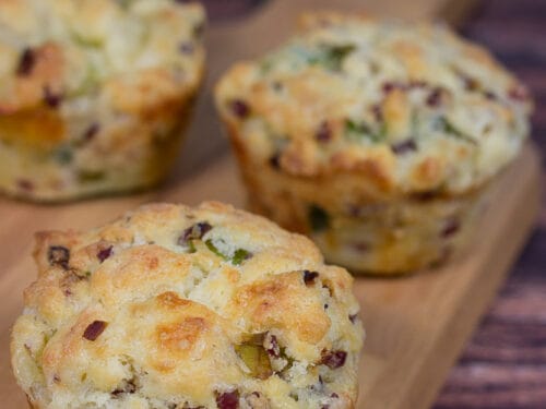 Drei herzhafte Muffins mit Speck und mit grünen Frühlingszwiebeln im Teig.
