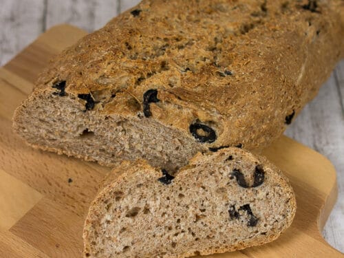 Vollkornbrot mit Olive, eine Scheibe geschnitten, auf einem Holzbrett.