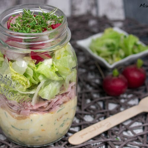 Salat im Glas mit Eiern, Schinken und Radieschen 3 Geschichteter Salat im Glas mit Schinken und frischem Salat in einem Einmachglas, serviert mit Radieschen und Kresse.