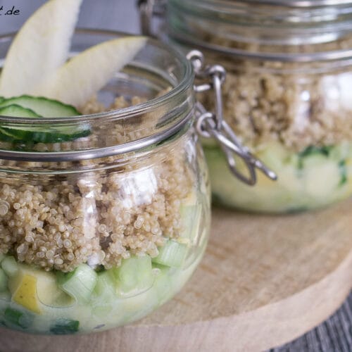 Zwei Salat im Glas mit Quinoa mit Gurke und Apfel zum Mitnehmen.