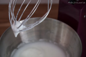 Eiweiß, das mit einem Schneebesen zu steifem, schaumigem Schnee geschlagen wird, geeignet für die Zubereitung von Eischnee.