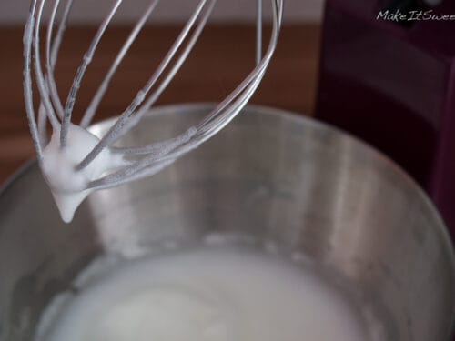 Eiweiß, das mit einem Schneebesen zu steifem, schaumigem Schnee geschlagen wird, geeignet für die Zubereitung von Eischnee.