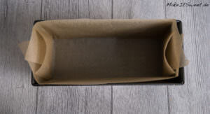 Eine mit braunem Pergamentpapier ausgelegte Laibform, bereit zum Backen.