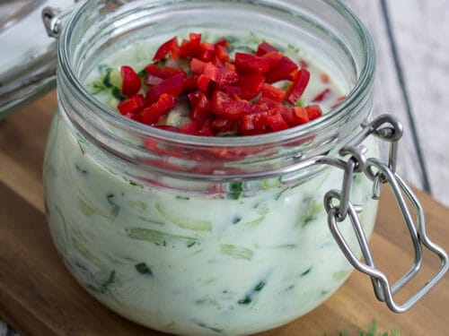 Ein Glas cremiger Gurken Salat mit Joghurt-Dill-Dressing, garniert mit Chili.