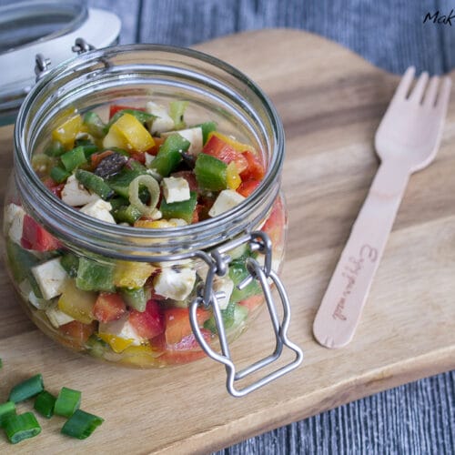 Griechischer Paprikasalat mit Feta und Oliven 3 Paprikasalat mit Feta im Glas, mit bunten Paprika und Fetawürfeln. Eine Holzgabel ist neben dem Glas platziert.