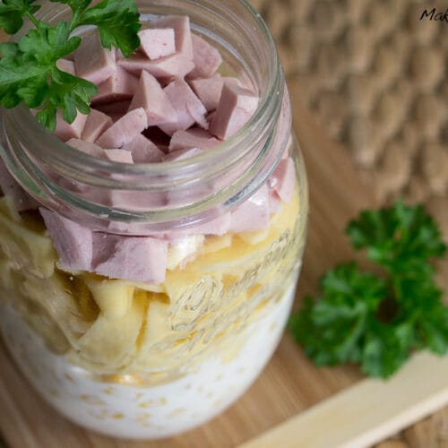 Nudelsalat mit Fleischwurst - Salat im Glas 3 Salat im Glas geschichtet mit Dressing, Nudeln, Fleischwurst und Petersilie auf ein Holzbrett stellen.