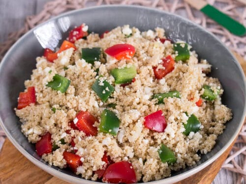Couscous-Salat mit gehackten grünen und roten Paprikaschoten in einer Schüssel.