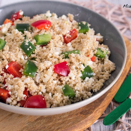 Schüssel mit Couscous-Salat mit gewürfelten roten und grünen Paprika und Feta.