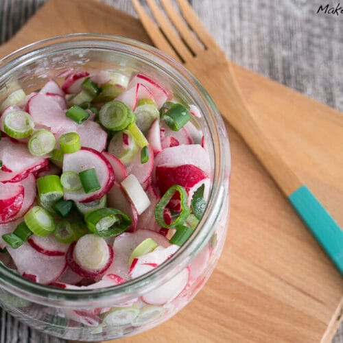 Radieschensalat mit Sahne 3 Glasgefäß mit Radieschensalat mit Sahne mit geschnittenen Radieschen und Lauchzwiebeln auf einem Holzbrett.