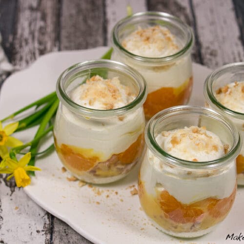 Vier Gläser Tiramisu mit Eierlikör, mit Sahne-, Frucht- und Krumenschichten.