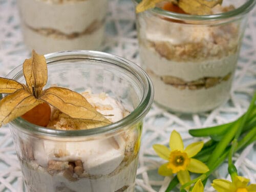 Drei Gläser mit geschichteten Desserts, die mit frischen Physalis belegt sind.