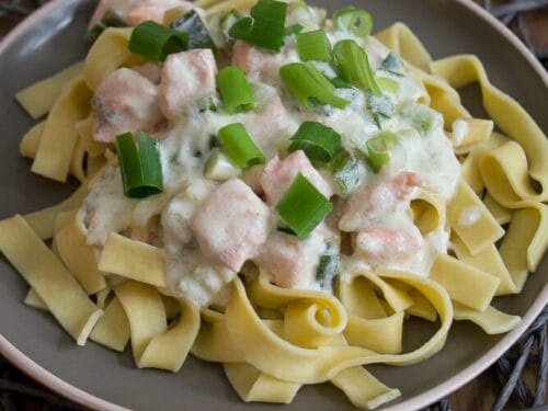 Breite Nudeln mit cremiger Lachssauce und Frühlingszwiebeln.