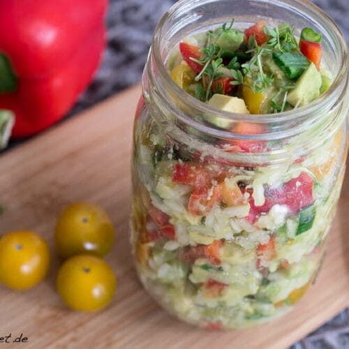 Reissalat mit Paprika und Avocado - Salat im Glas 3 Reissalat im Glas mit Tomaten, roter Paprika und Chili auf einem Holzbrett - Reissalat mit Paprika Zutaten sichtbar.