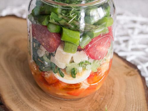 Glasgefäß mit Schichten von Spargelsalat, Eischeiben, Käse und Kresse.