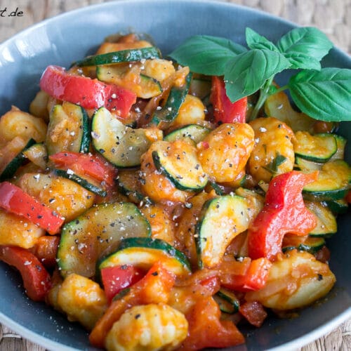 Lauwarmer Gnocchi Salat mit Paprika und Zucchini 3 Schüssel mit Gnocchi-Salat mit Paprika, Zucchini, Tomatensauce und frischem Basilikum.